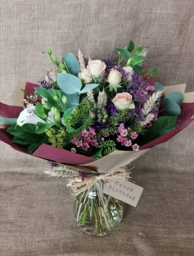 Pickle Jar Arrangement - A beautiful selection of florist choice seasonal flowers presented in a large pickle jar. Finished off with a raffia bow and luggage tag.